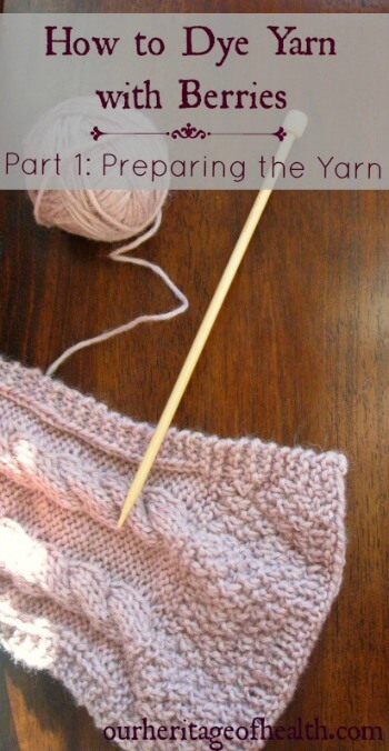 Ball of pale lavender colored yarn next to knitting needle and part of knitted scarf