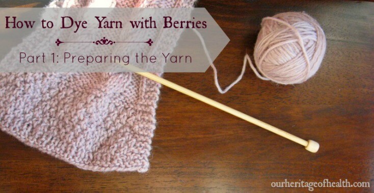 Ball of pale lavender colored yarn next to knitting needle and part of knitted scarf
