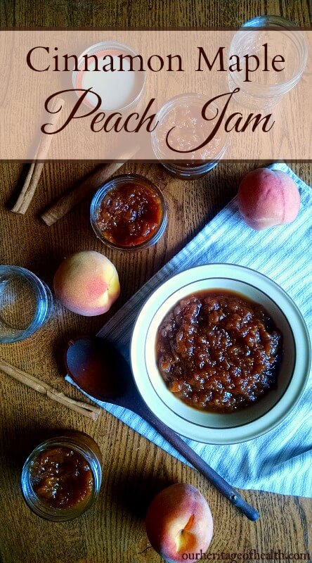 Bowl and Mason jars full of peach jam on table with peaches and spoon.